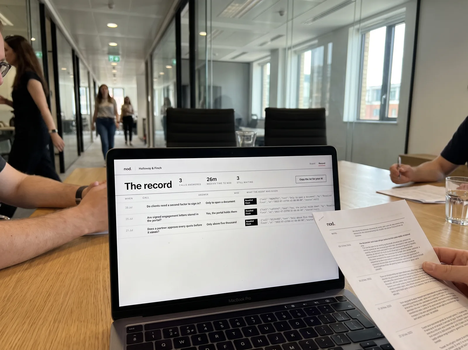 A laptop on a meeting-room table showing the record: a dated table of answered calls with who decided each one